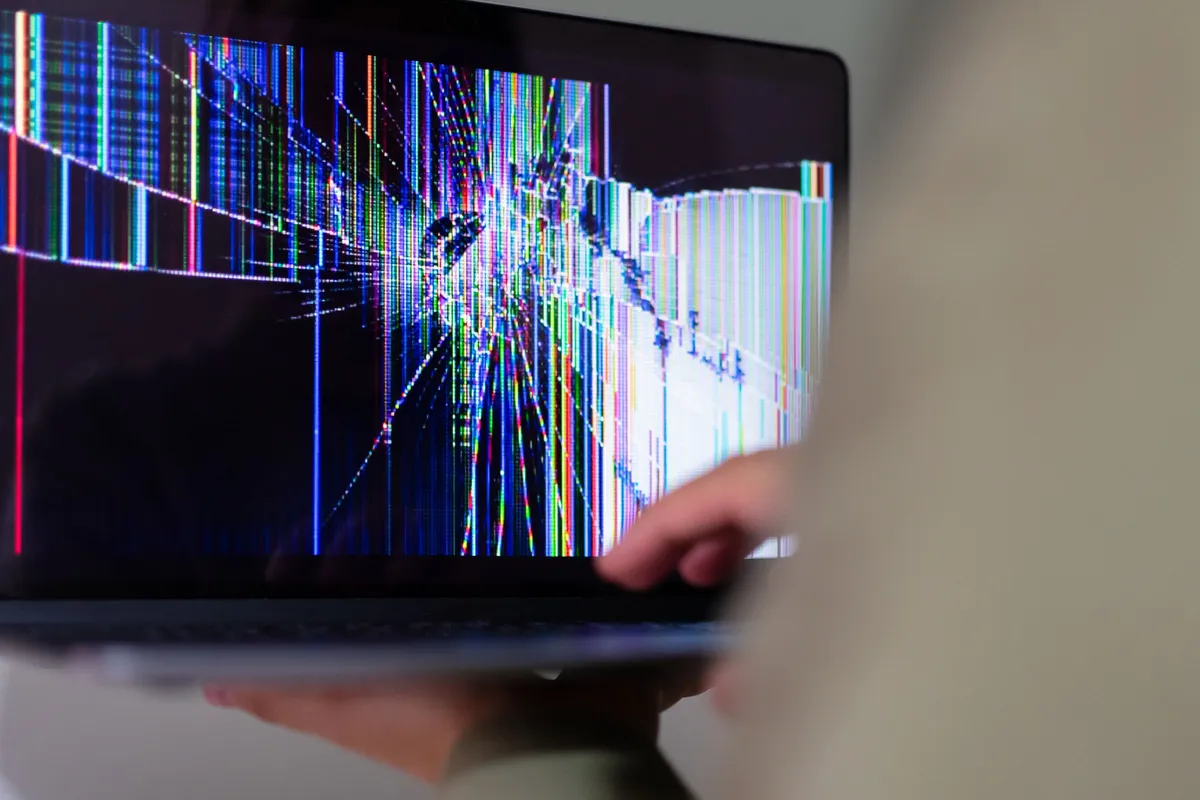 Laptop mit gesprungenem Bildschirm und bunten Bildstörungen