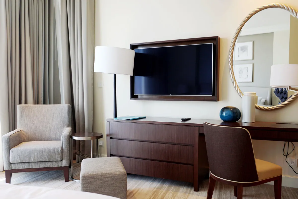 Hotelzimmer mit Sessel, Schreibtisch und Wandfernseher