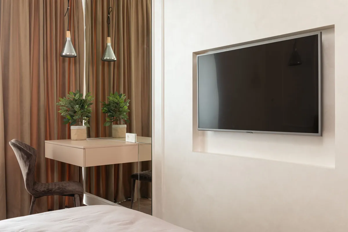 Wandfernseher in einer Nische neben einem kleinen Schreibtisch mit Pflanzen