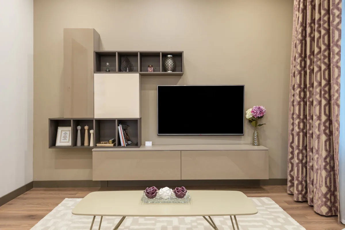 Fernseher in einer hellen Wohnwand mit Regalfächern und Couchtisch