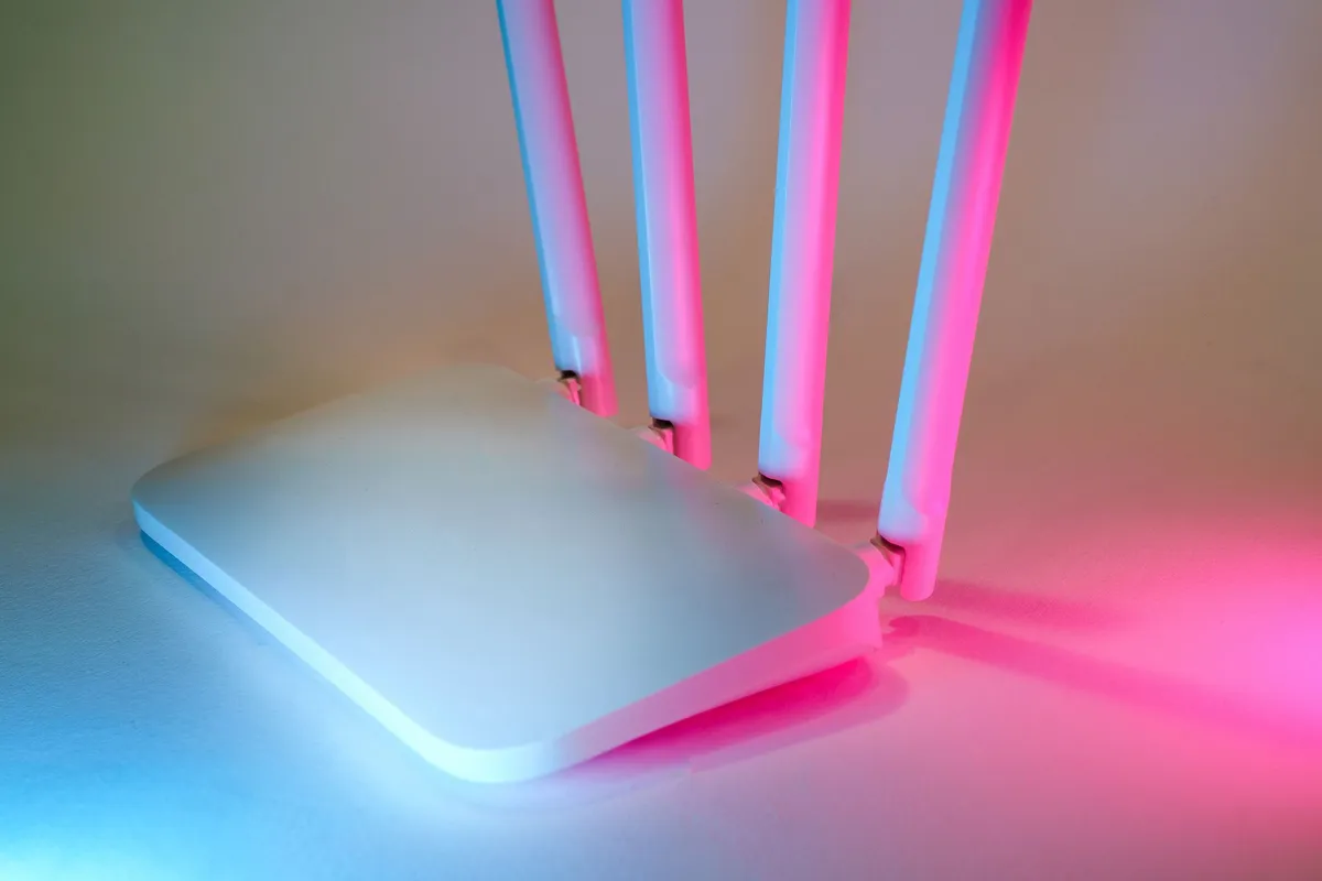 Weißer WLAN-Router mit vier Antennen in blauem und rosa Licht