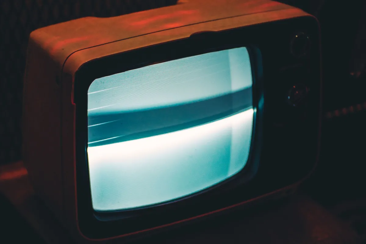 Alter Röhrenfernseher mit grau leuchtendem Bildschirm in einem dunklen Raum