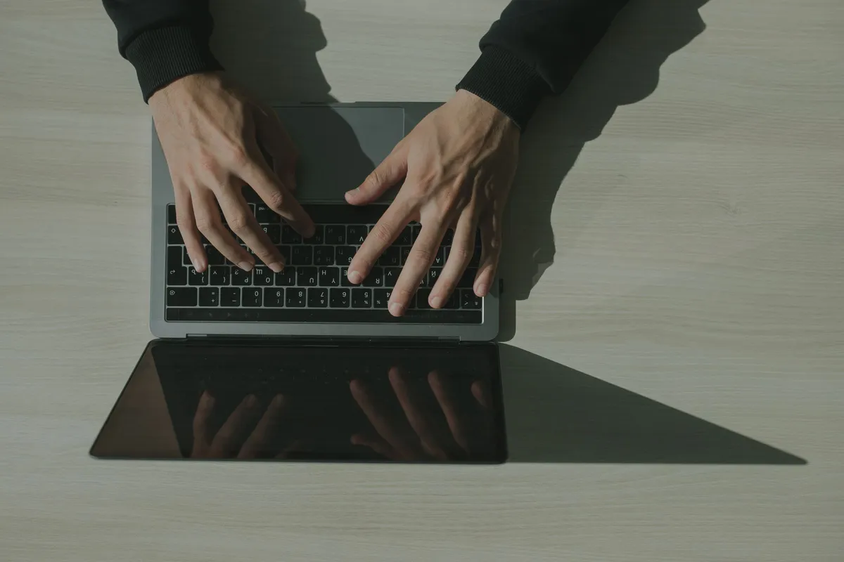 Hände tippen von oben gesehen auf der Tastatur eines Laptops