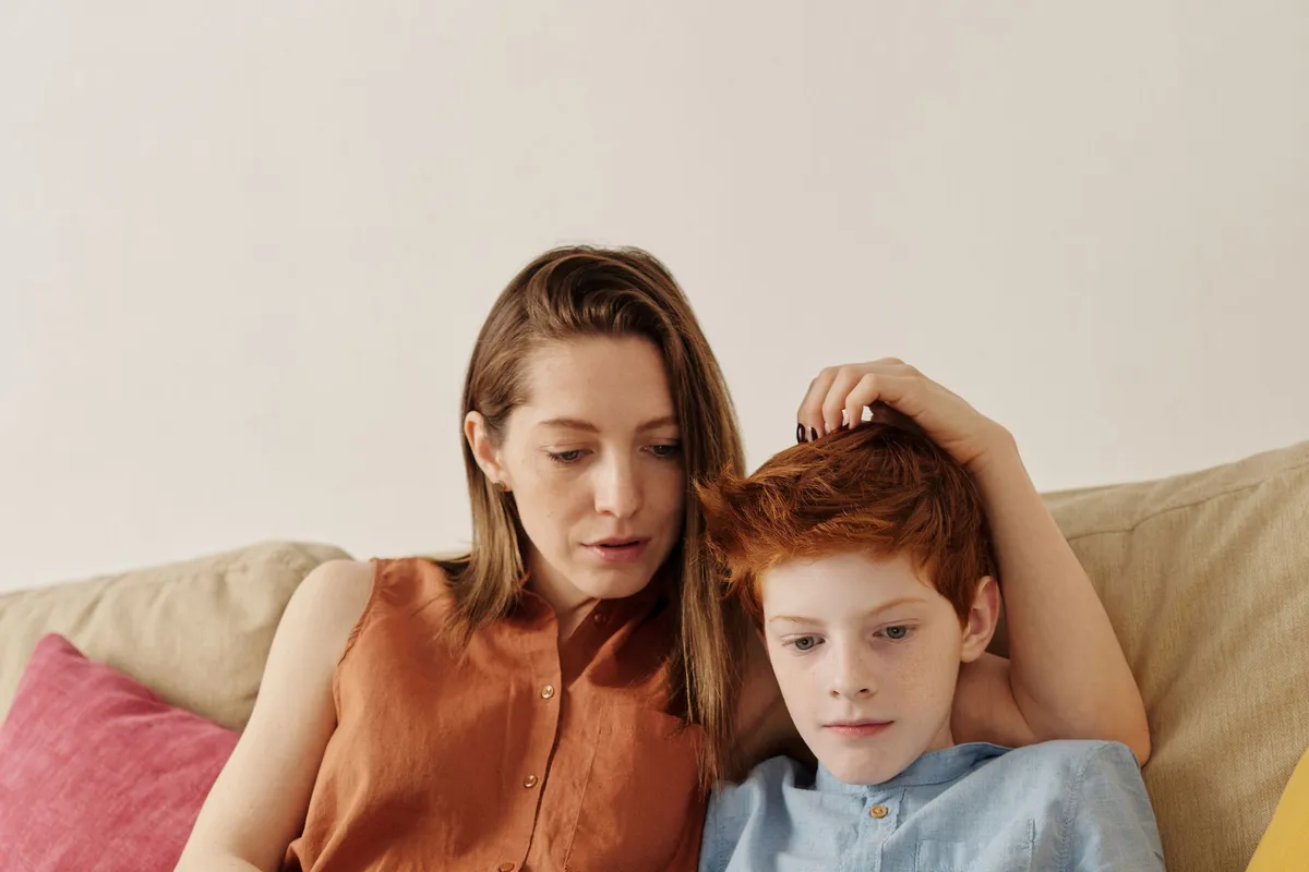 Mutter und Sohn schauen auf dem Sofa gemeinsam auf ein Tablet